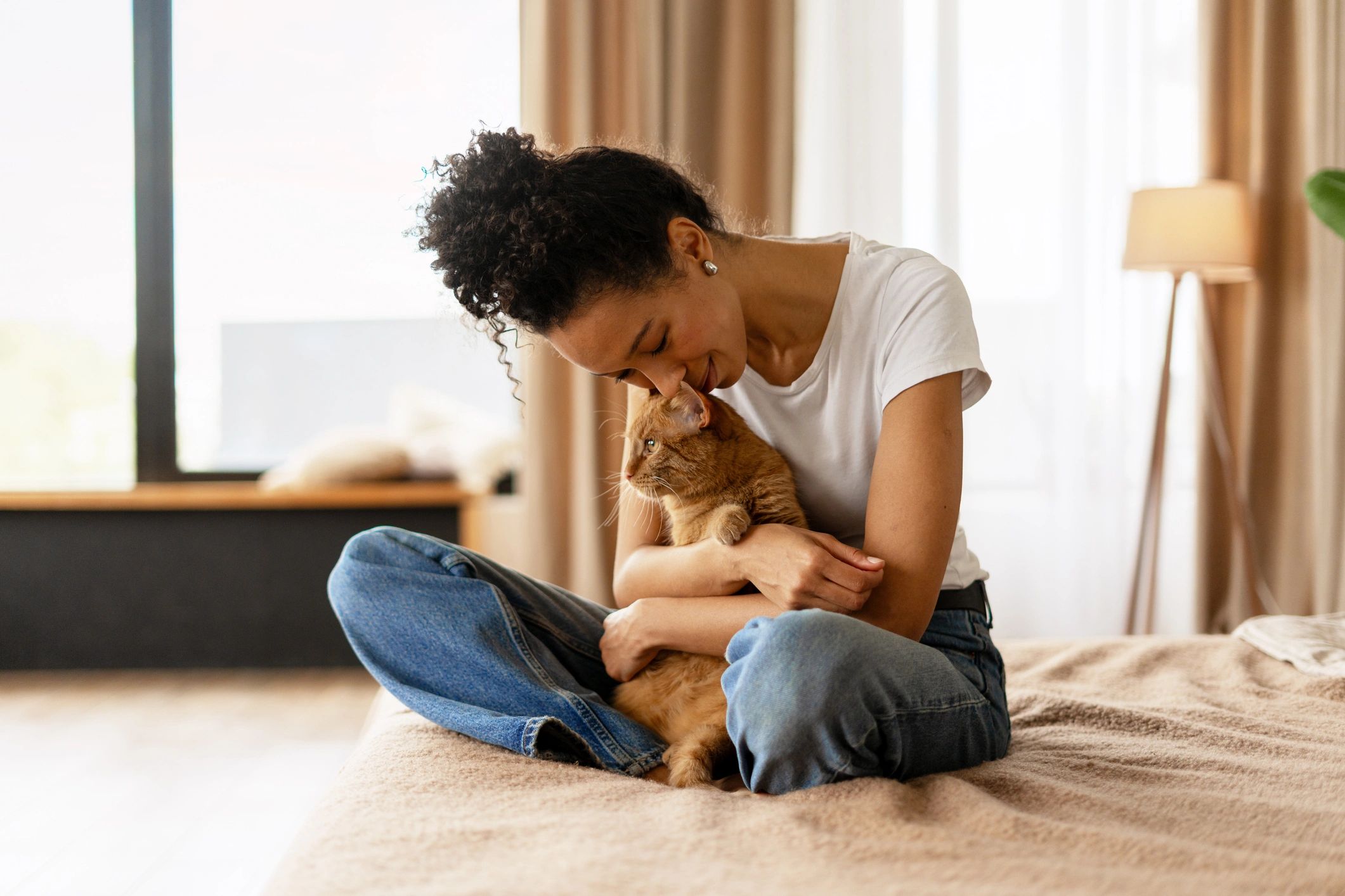 Woman showing affection to her ginger cat at home